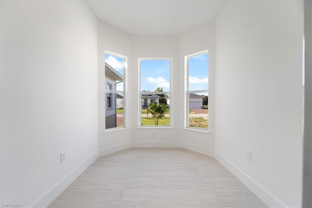 Unfurnished room with baseboards and plenty of natural light