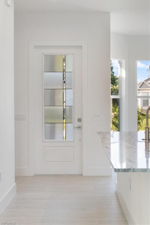 Doorway with baseboards and light wood-style flooring