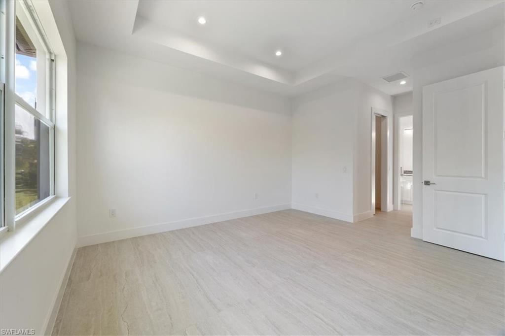 Empty room with recessed lighting, baseboards, light wood-type flooring, and visible vents