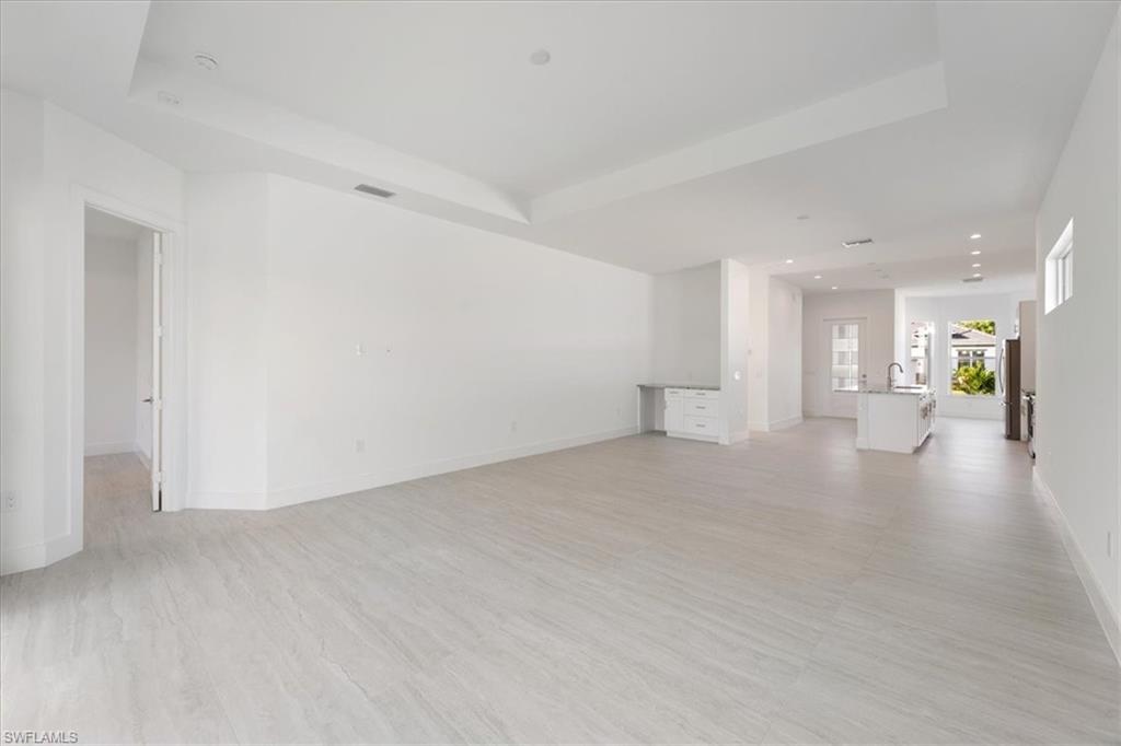 Unfurnished living room featuring recessed lighting, a tray ceiling, and light wood finished floors