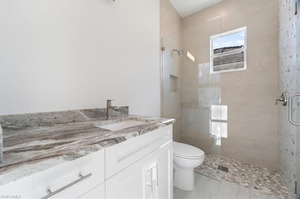 Bathroom with vanity, toilet, and tiled shower