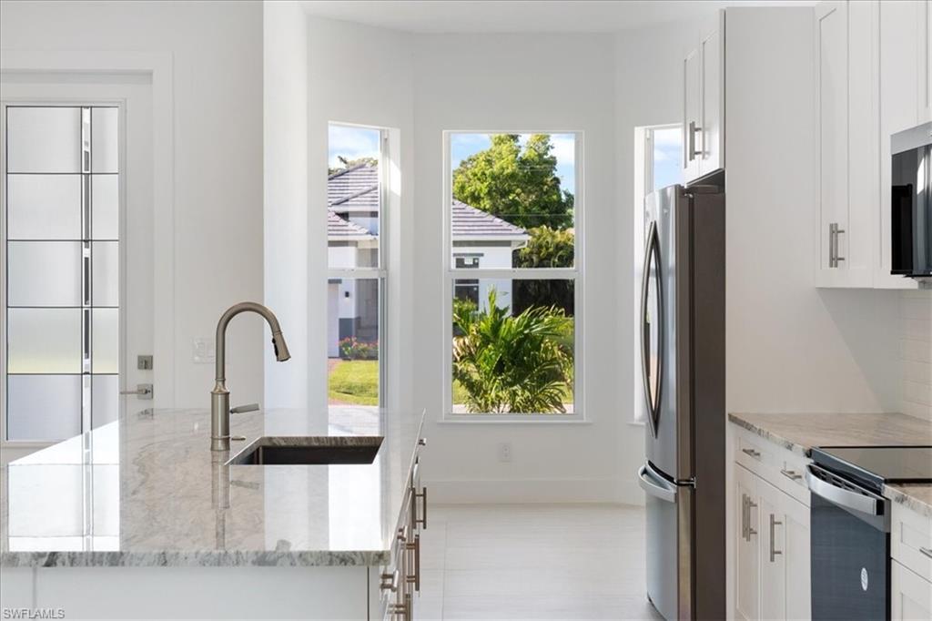 Kitchen with plenty of natural light, a sink, white cabinetry, and appliances with stainless steel finishes
