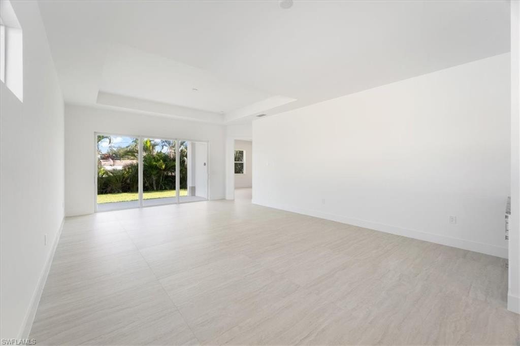 Empty room featuring baseboards and a tray ceiling