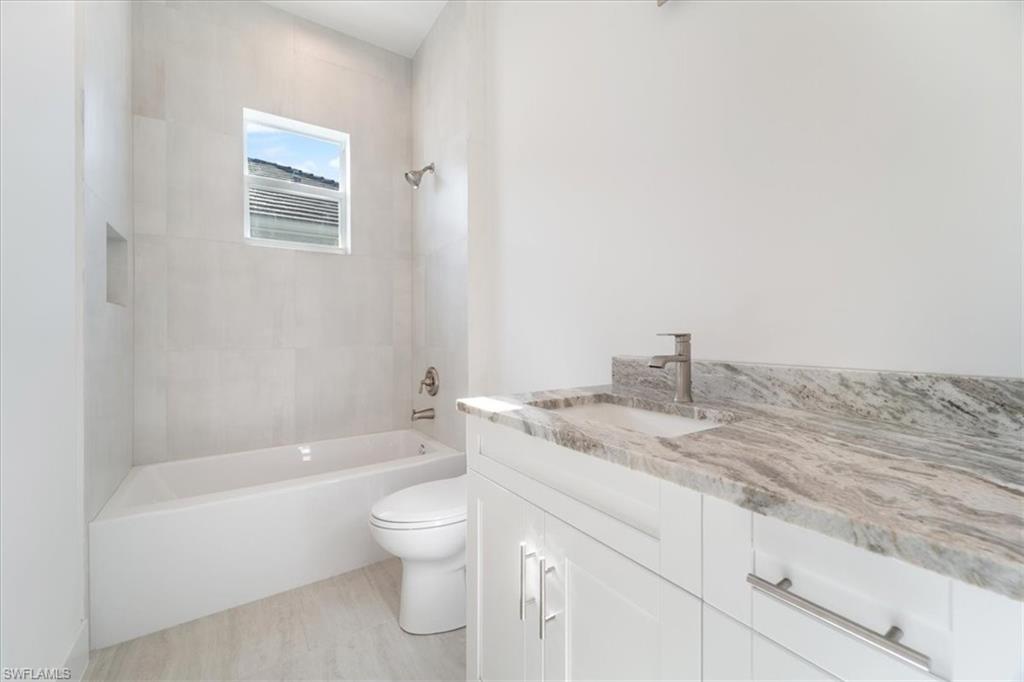 Bathroom with shower / bath combination, vanity, and toilet