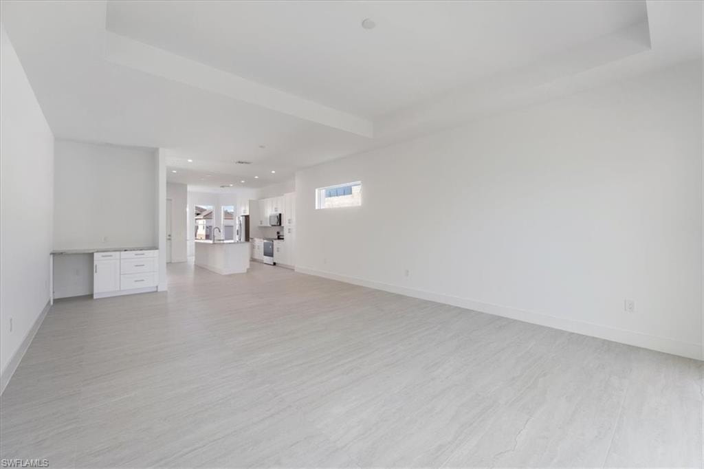 Unfurnished living room featuring baseboards, recessed lighting, and light wood-style flooring