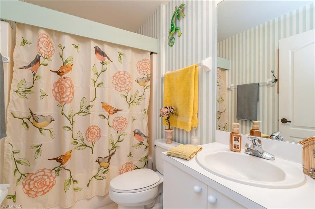 Bathroom featuring curtained shower, vanity, and toilet