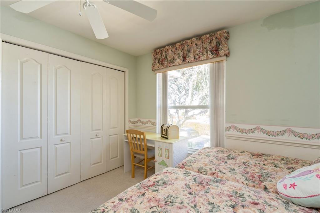 Carpeted bedroom with ceiling fan and a closet