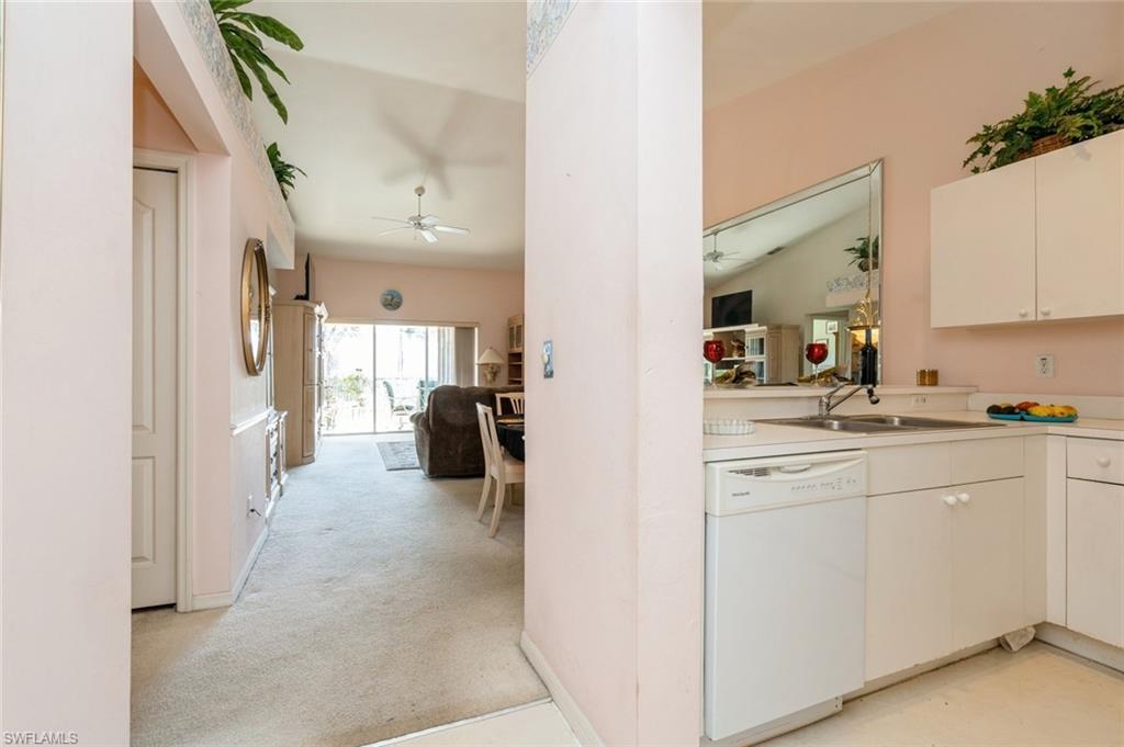 Kitchen with white cabinetry, dishwasher, ceiling fan, sink, and light carpet