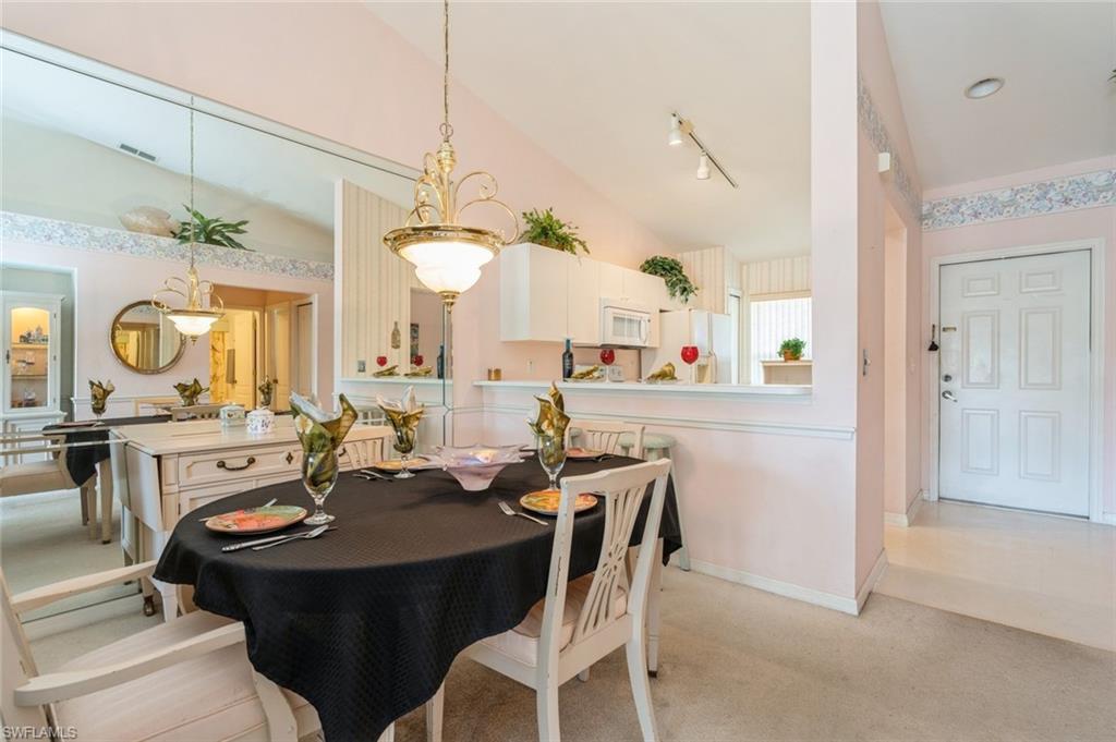 Carpeted dining area with track lighting and lofted ceiling