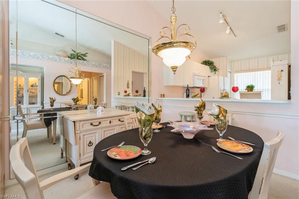 Carpeted dining space with rail lighting and vaulted ceiling