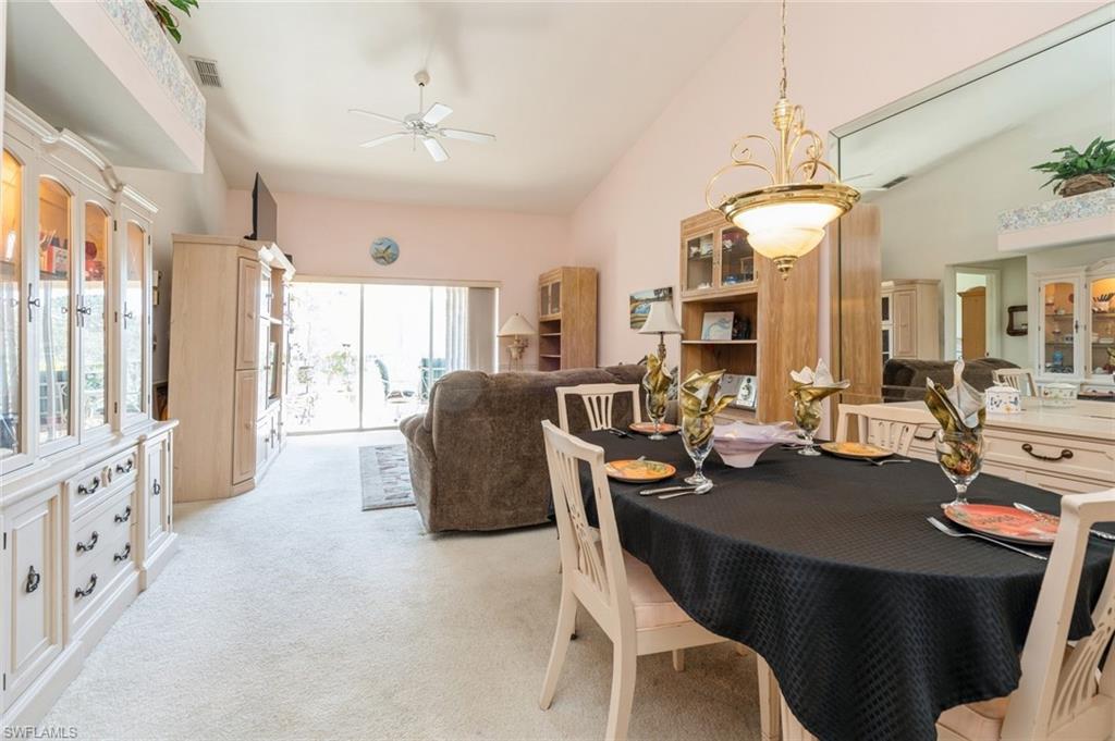Carpeted dining room featuring ceiling fan and high vaulted ceiling