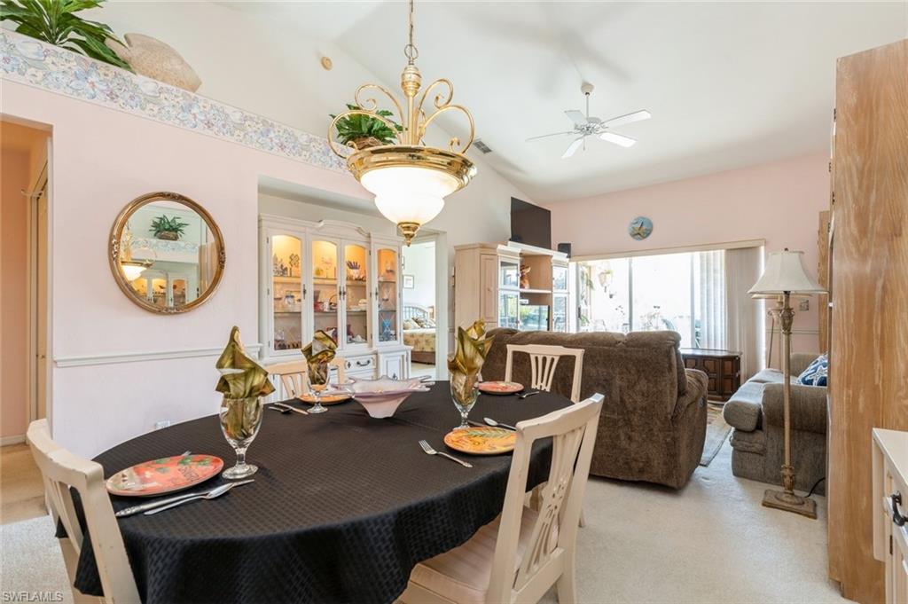 Dining space featuring ceiling fan, light colored carpet, and lofted ceiling