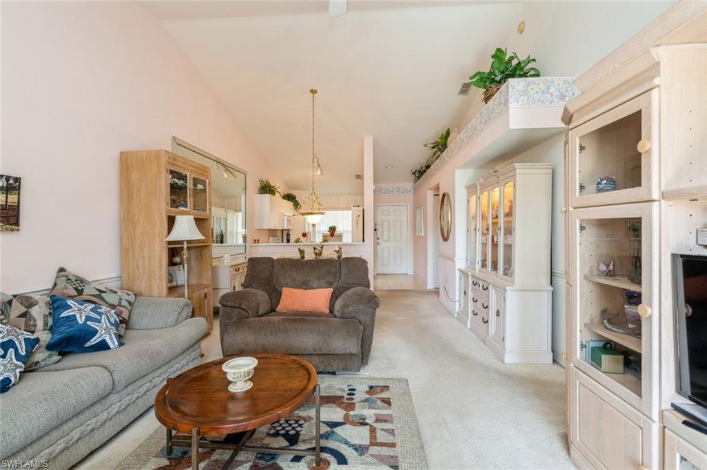 Carpeted living room featuring lofted ceiling