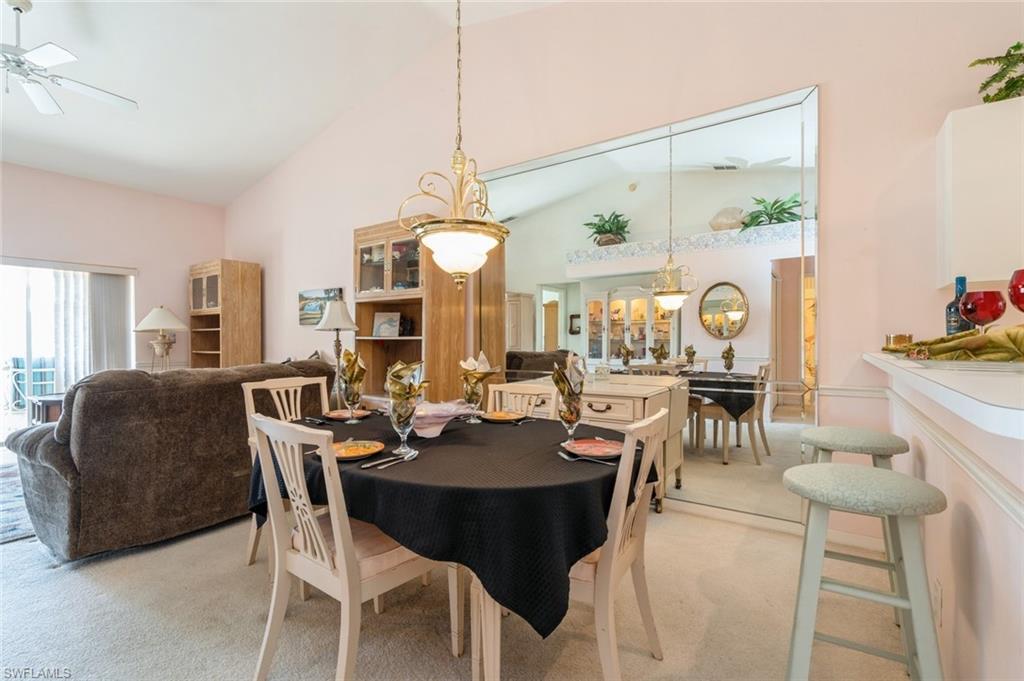 Dining space featuring light colored carpet, ceiling fan, and lofted ceiling
