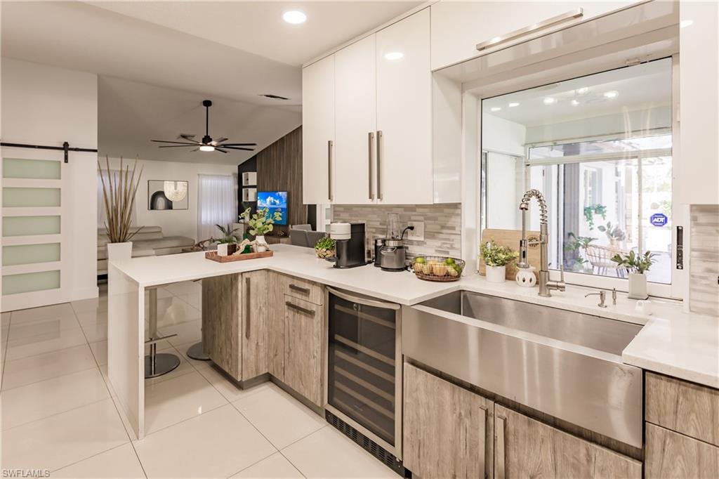 Kitchen with white cabinetry, beverage cooler, a barn door, lofted ceiling, and light tile patterned floors