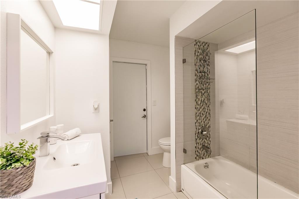 Full bathroom featuring a skylight, vanity, shower / tub combo with curtain, tile patterned flooring, and toilet