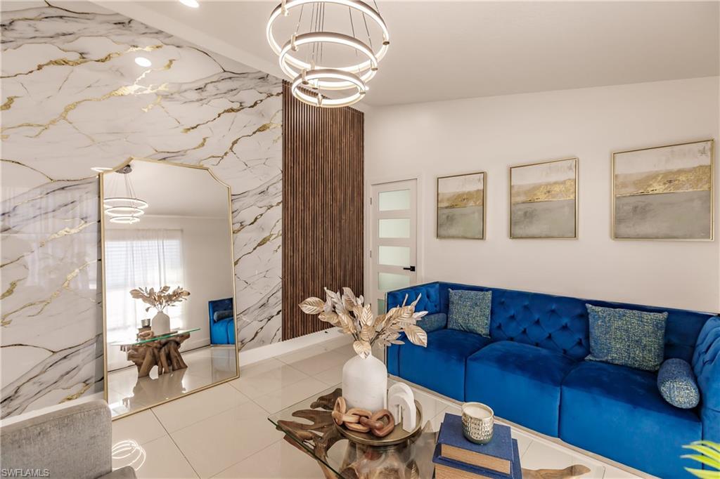 Living room featuring vaulted ceiling, tile patterned floors, and a notable chandelier