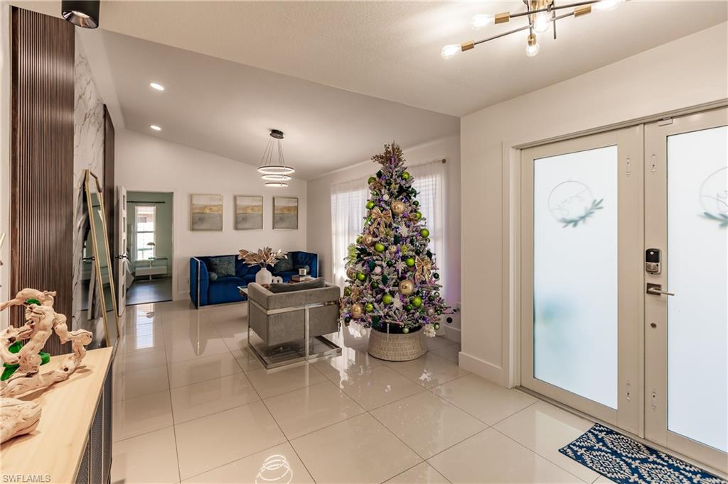 Tiled foyer entrance with plenty of natural light, a chandelier, and lofted ceiling