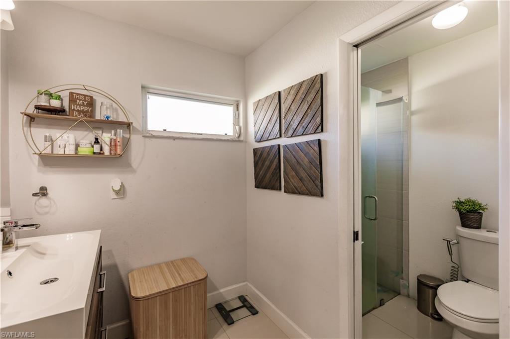 Bathroom featuring tile patterned floors, a shower with door, vanity, and toilet