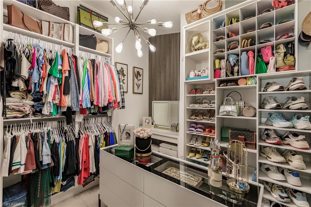 Spacious closet featuring a notable chandelier and light tile patterned flooring
