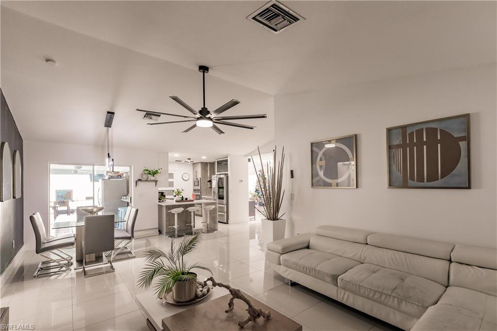 Living room with light tile patterned floors, vaulted ceiling, and ceiling fan