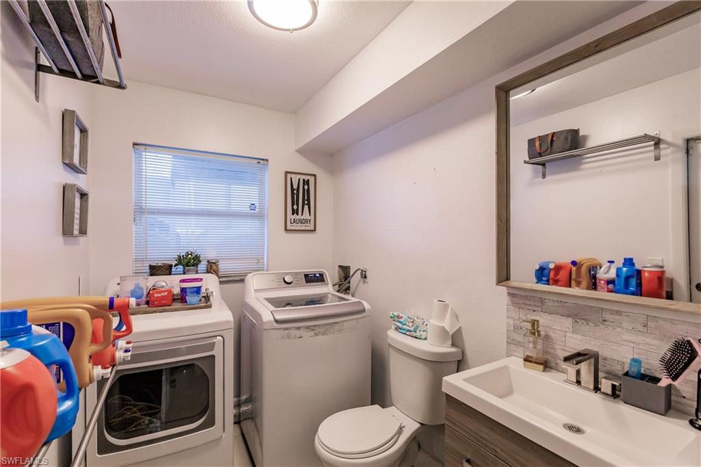 Bathroom with toilet, washing machine and dryer, backsplash, and vanity
