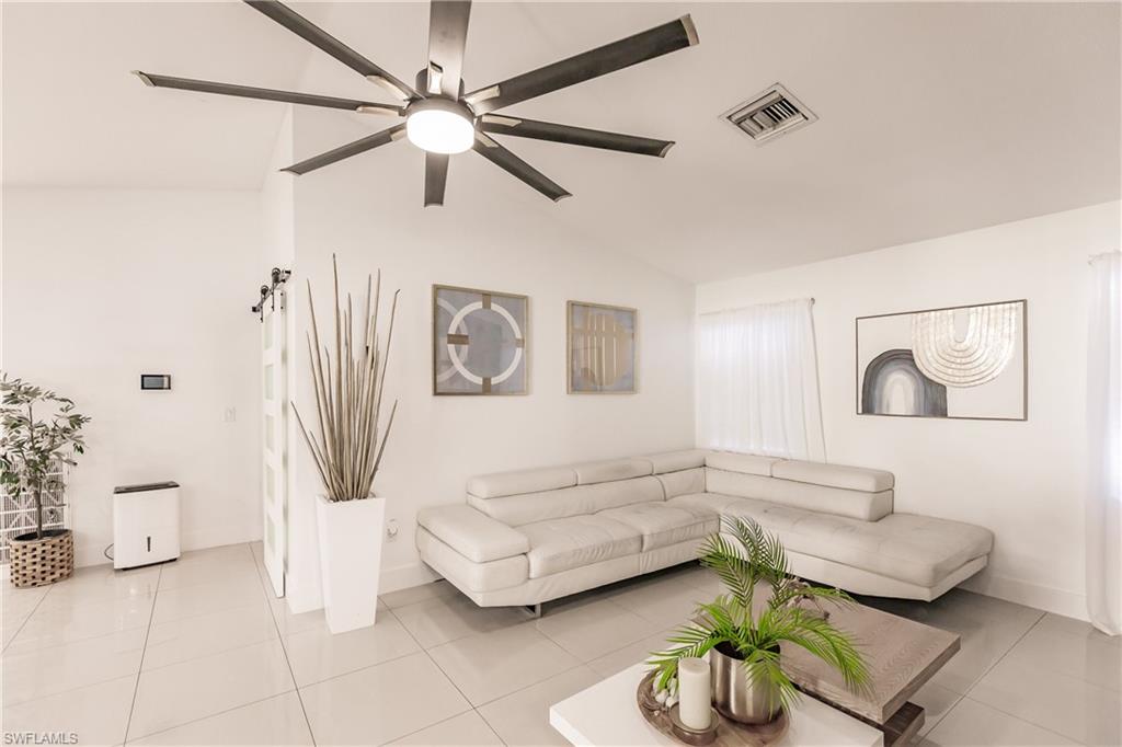 Tiled living room featuring ceiling fan and vaulted ceiling