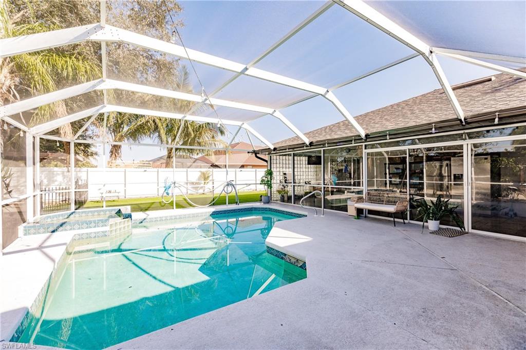 View of pool featuring glass enclosure, an in ground hot tub, and a patio