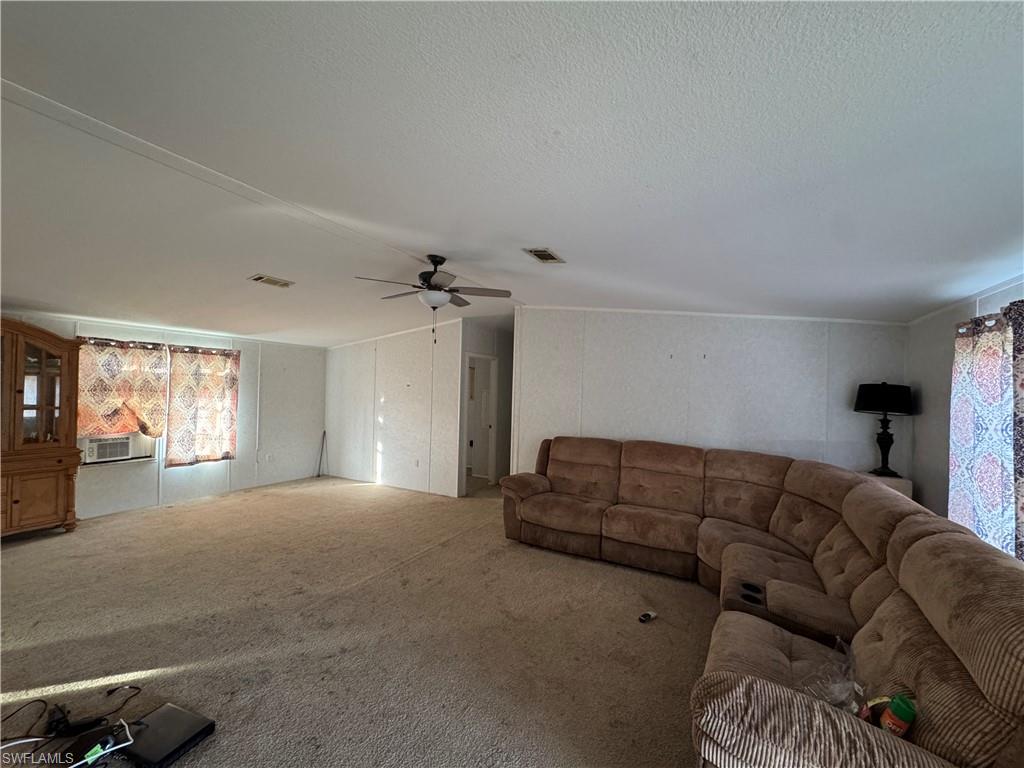 Living room featuring a textured ceiling, carpet floors, and ceiling fan