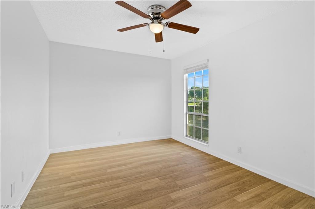 Empty room with a textured ceiling, light wood-type flooring, and ceiling fan