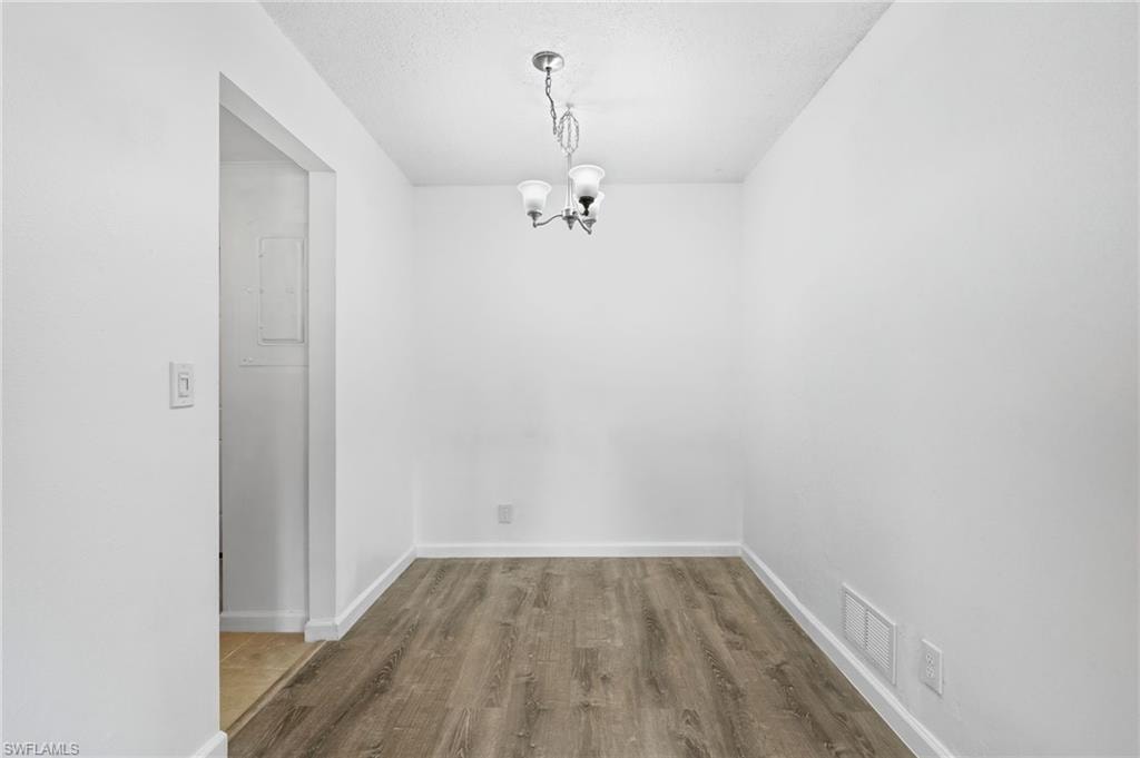 Unfurnished dining area with LVP wood-style floors and an inviting chandelier