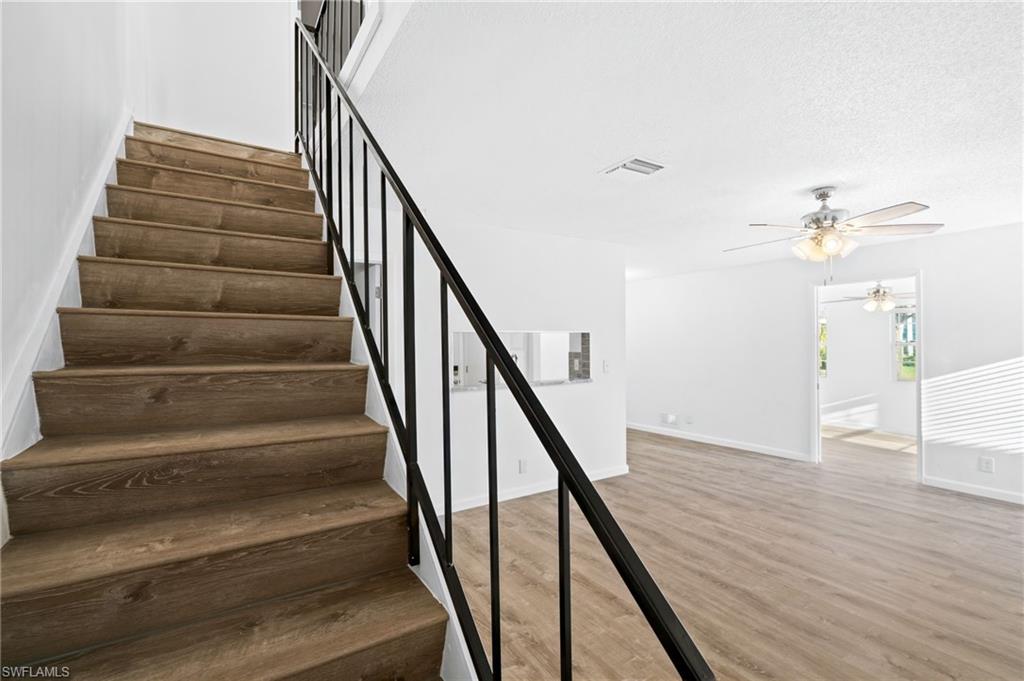Stairway featuring wood-type flooring, a textured ceiling, and ceiling fan