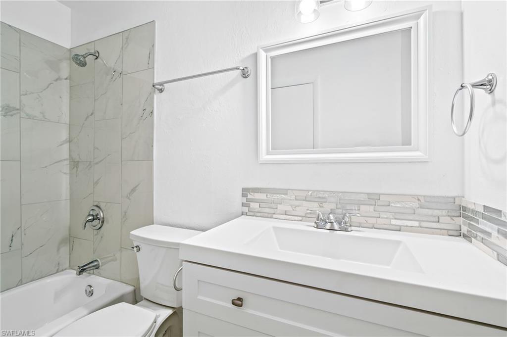 Full bathroom featuring vanity, tiled shower / bath combo, tasteful backsplash, and toilet. Second Floor.