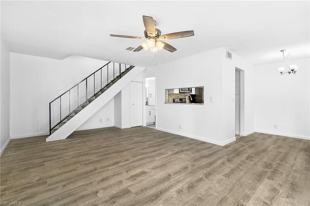 Unfurnished living room featuring wood-type flooring and ceiling fan with notable chandelier