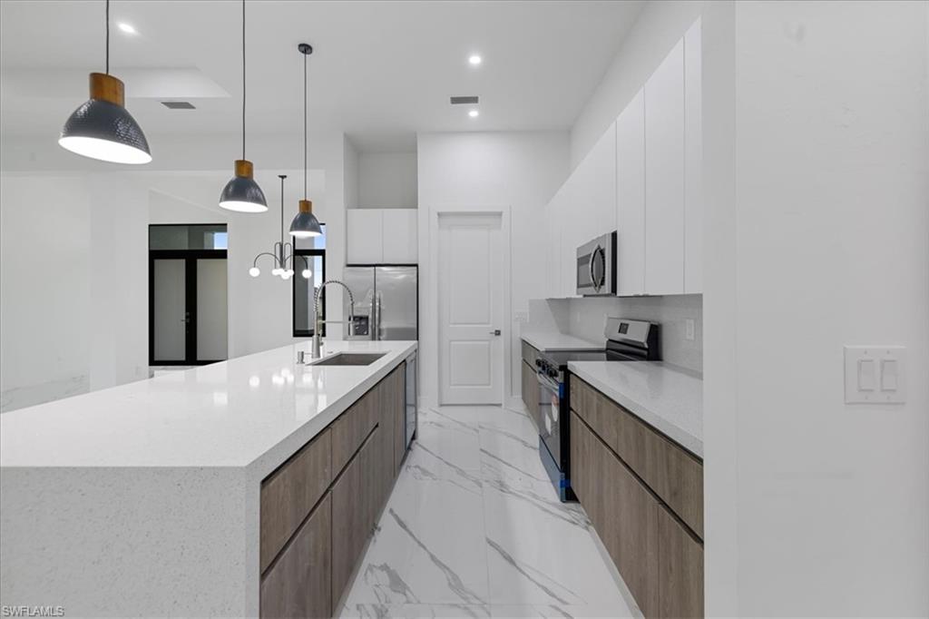 Kitchen featuring a spacious island, pendant lighting, white cabinets, and stainless steel appliances