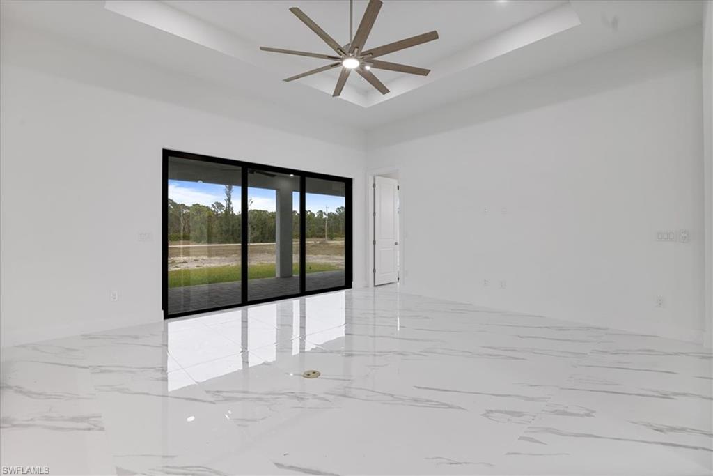 Unfurnished room featuring ceiling fan and a tray ceiling
