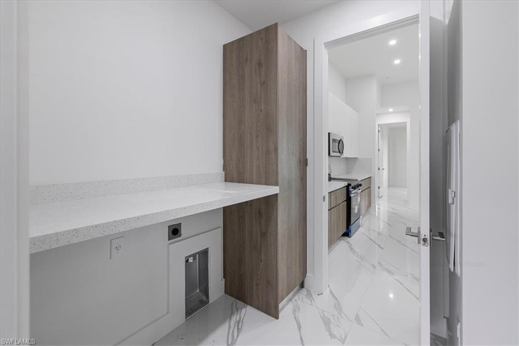 Kitchen featuring light stone countertops, built in desk, and stainless steel appliances
