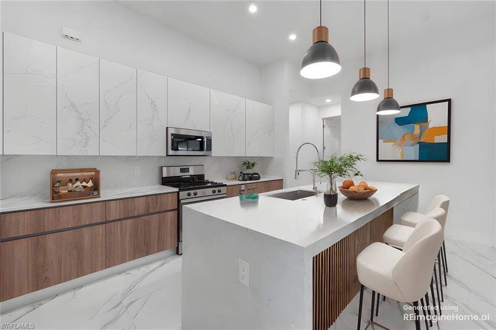 Kitchen with an island with sink, a breakfast bar area, appliances with stainless steel finishes, pendant lighting, and sink