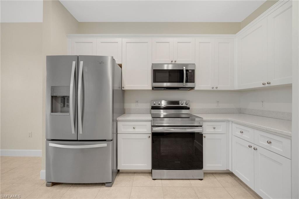 Kitchen featuring white cabinets, light tile patterned floors, and appliances with stainless steel finishes