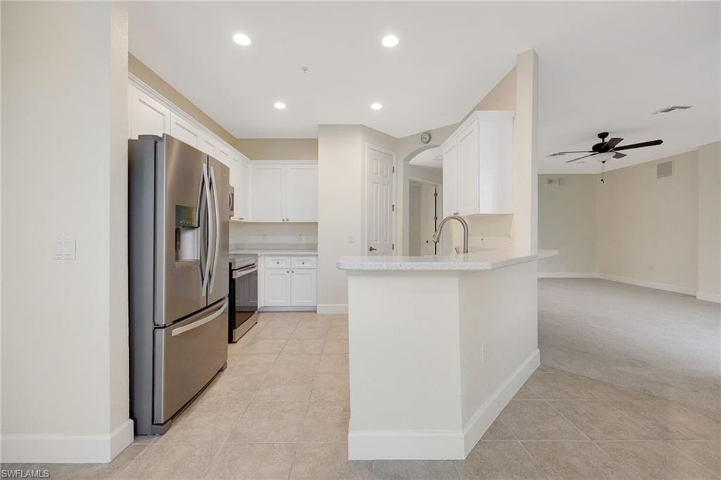 Kitchen featuring light carpet, ceiling fan, appliances with stainless steel finishes, sink, and white cabinetry