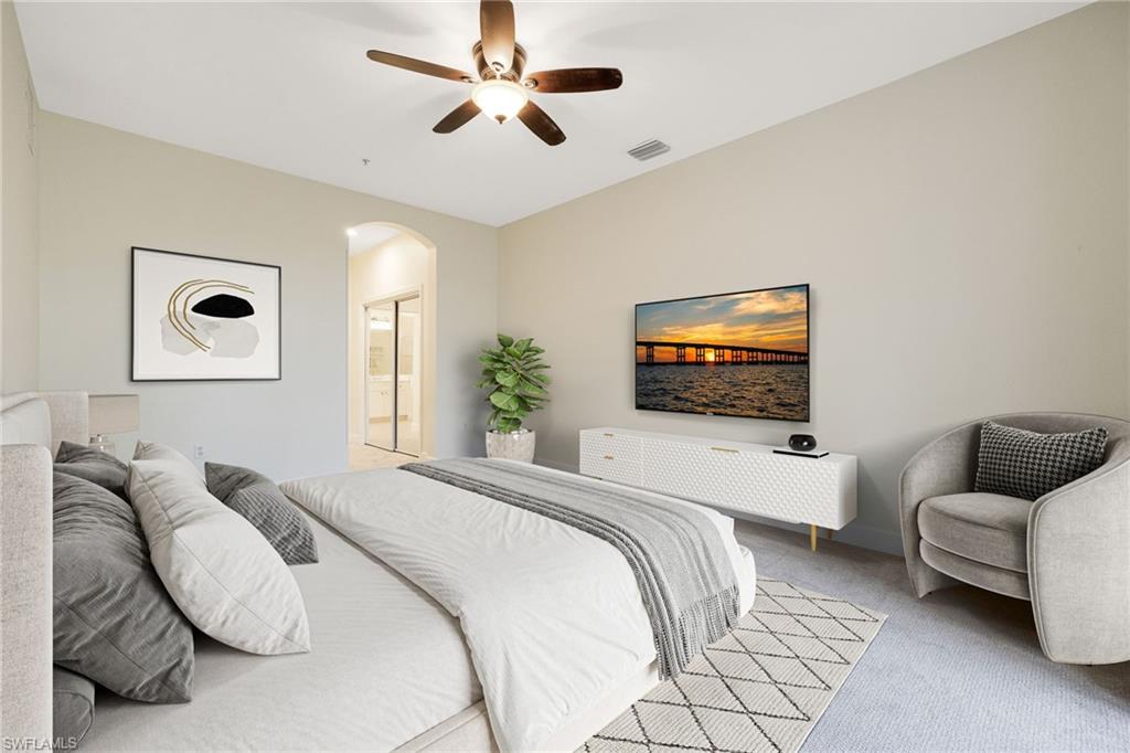 Carpeted bedroom featuring a ceiling fan, ensuite bathroom, and arched walkways