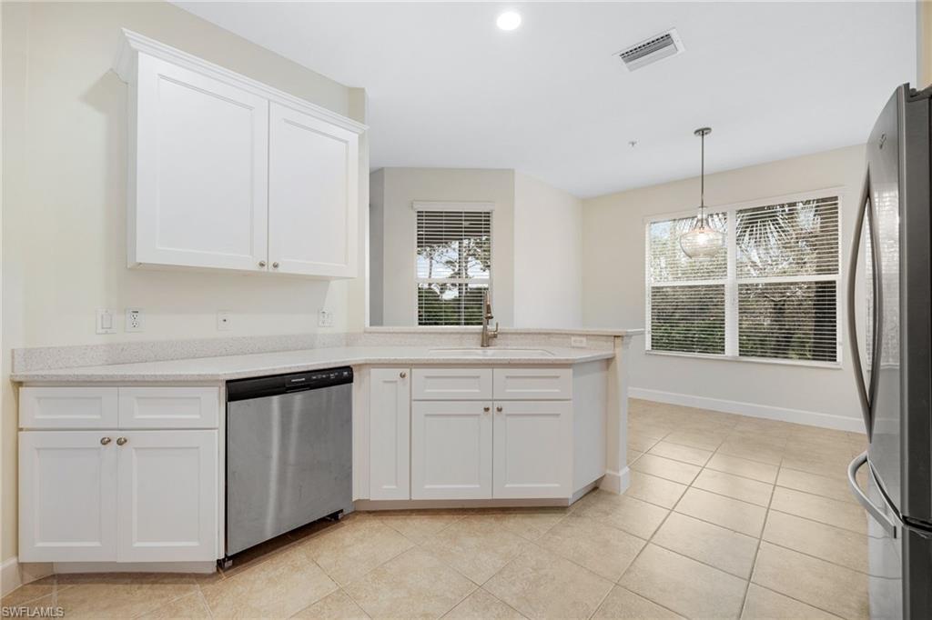 Kitchen with appliances with stainless steel finishes, white cabinetry, sink, hanging light fixtures, and light tile patterned floors