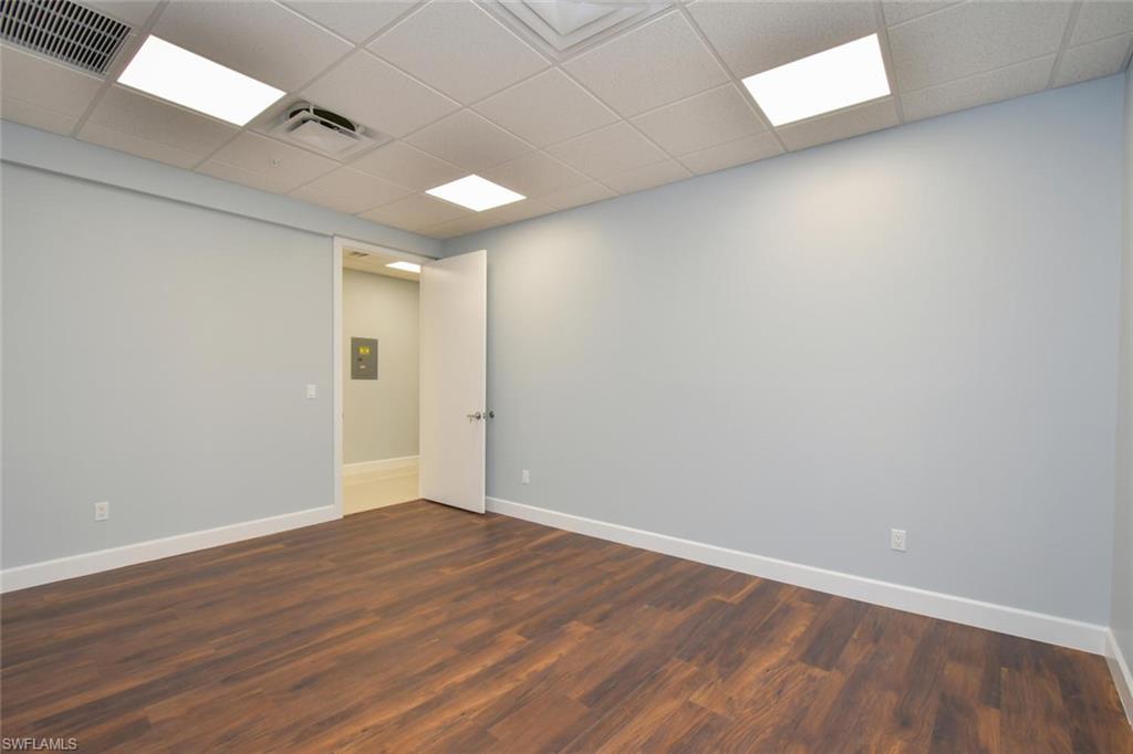 Unfurnished room with dark hardwood / wood-style flooring and a paneled ceiling