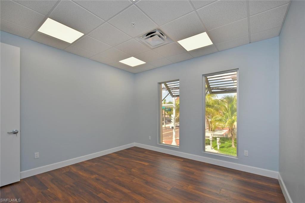 Empty room with a drop ceiling and dark hardwood / wood-style flooring
