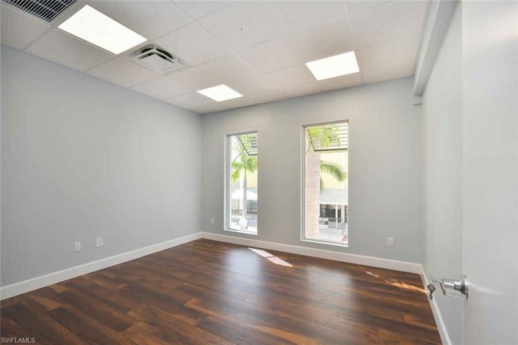 Empty room featuring dark wood-type flooring and a drop ceiling
