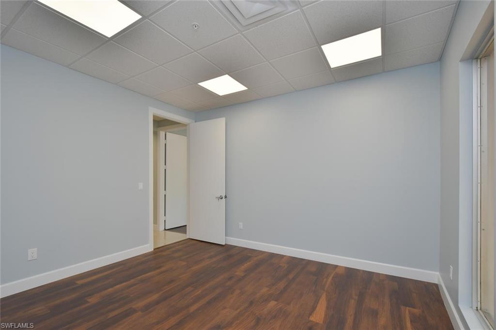 Unfurnished room with a drop ceiling and dark wood-type flooring