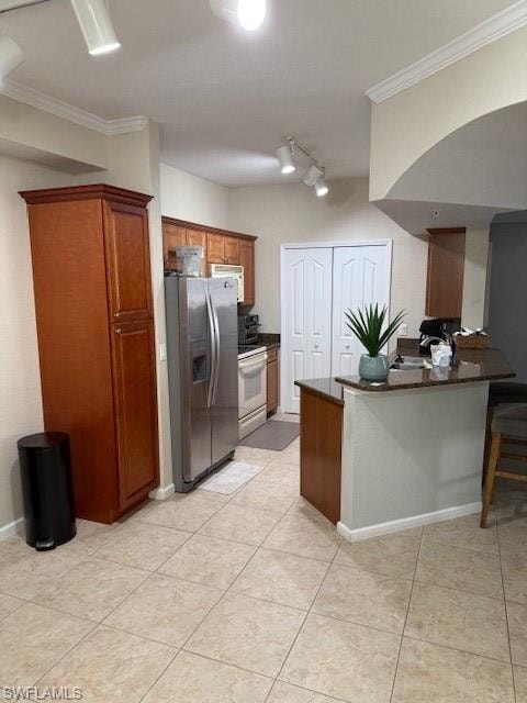 Kitchen with crown molding, a breakfast bar area, stove, fridge, and kitchen peninsula