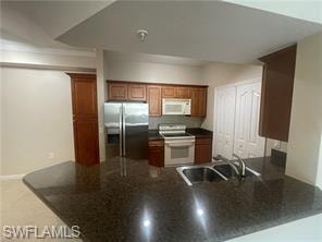 Kitchen with sink, white appliances, and kitchen peninsula