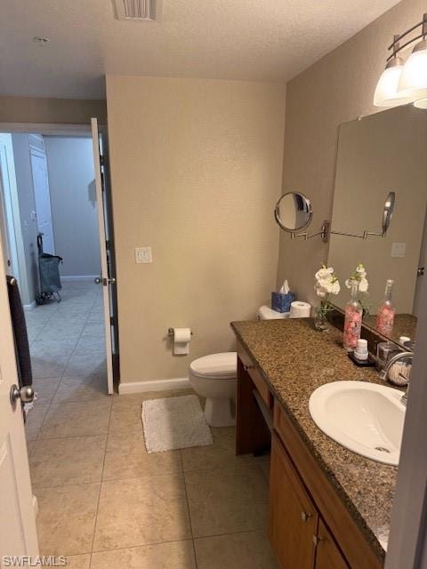 Bathroom featuring vanity, toilet, tile patterned flooring, and a textured ceiling