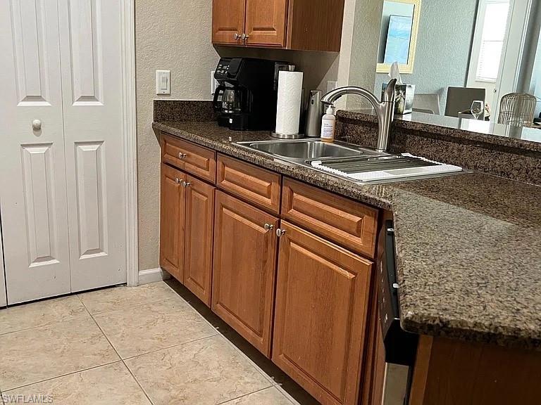 Kitchen featuring sink, light tile patterned flooring, and dark stone counters